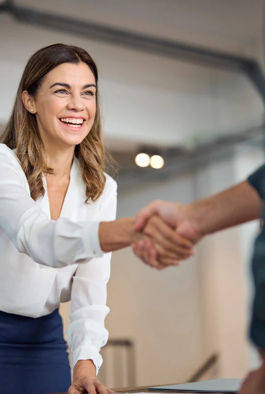 Eine lächelnde Frau schüttelt die Hand und symbolisiert damit die Partner Bank als innovativen, dynamischen und professionellen Arbeitgeber.